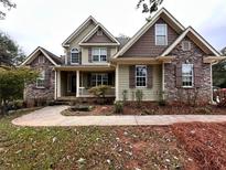 Charming two-story home with a stone and shingle facade, covered porch, and landscaped front yard at 2443 High Meadows Ct, Conyers, GA 30094