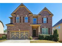 Charming two-story brick home featuring a two-car garage and well-maintained landscaping under a clear blue sky at 2935 Wardlaw Ln, Buford, GA 30519