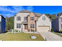 Inviting two-story home with a brick and stone facade, complemented by a well-manicured lawn and a two-car garage at 4488 Mantova Dr, Buford, GA 30519