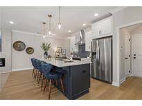 A kitchen with stainless steel appliances, navy blue island with seating, and white cabinets at 4529 Twinberry Dr, Powder Springs, GA 30127