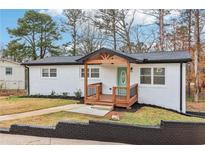 Charming renovated single-story home with brick exterior, wood porch and turquoise door at 5901 Miller Rd, Austell, GA 30106