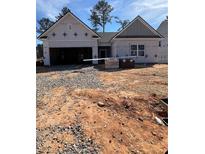 New construction home with open garage door and landscaping materials on the front lawn at 146 Silverton Dr, Dacula, GA 30019