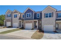 View of newly built townhomes with brick facades, garages, and well-maintained lawns at 7016 Fringe Flower Dr # 88, Austell, GA 30168