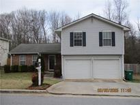 Two-story home with gray siding, a brick accent wall, an attached two-car garage, and a well-manicured front lawn at 734 Kilkenny Cir, Lithonia, GA 30058