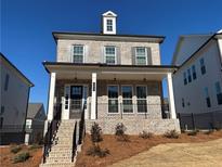 Charming brick home featuring a welcoming front porch, dormer window, and professionally landscaped yard at 104 Stonehouse Dr, Cumming, GA 30040