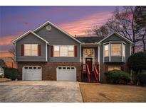 Charming two-story home featuring gray siding, brick accents, and a well-manicured lawn at sunset at 2901 Soapstone Ct, Powder Springs, GA 30127