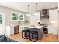 Modern kitchen boasts white cabinets, gray island, stainless appliances, and stylish pendant lighting at 1208 Thomas Rd, Decatur, GA 30030