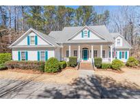Charming home featuring a covered front porch, vibrant turquoise accents, and lush landscaping at 3870 Ryans Lake Ter, Cumming, GA 30040