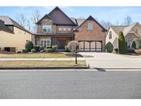 Elegant two-story home featuring a brick and stone facade, well-manicured landscaping, and a three-car garage at 1300 Primrose Park Rd, Sugar Hill, GA 30518