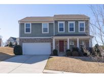 Charming two-story home with brick and siding exterior, showcasing a well-maintained front yard and attached two car garage at 1530 Avalon Creek Rd, Sugar Hill, GA 30518