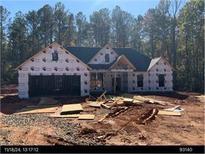 New construction featuring an attached two-car garage and a modern roofline, surrounded by a wooded lot at 247 Harmony Ridge Dr, Temple, GA 30179