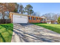 Charming brick home with a well-maintained lawn, long driveway, and attached garage at 4101 Spring Meadow Rd, Tucker, GA 30084