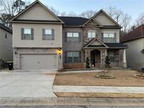 Charming two-story home featuring a mix of stone and siding, with a two-car garage and manicured front yard at 5215 Tye Trl, Fairburn, GA 30213