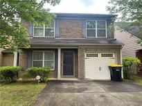 Charming two-story brick home with gray shutters, well-manicured lawn, and attached one-car garage at 312 Lauren Dr, Fairburn, GA 30213