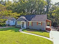 Charming home featuring a manicured lawn, gray brick, and a covered side porch at 672 Quillian Ave, Decatur, GA 30032