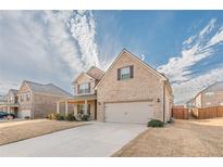 Charming two-story brick home featuring an attached two-car garage and covered front porch at 879 Tranquil Way, Hampton, GA 30228