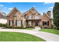 Beautiful brick and stone home featuring manicured lawn, circular driveway, and an inviting front porch at 8760 Colonial Pl, Duluth, GA 30097