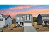 Charming two-story home featuring a brick and siding exterior, attached garage, and professionally landscaped front yard at 4290 Montberry Ln, Fairburn, GA 30213