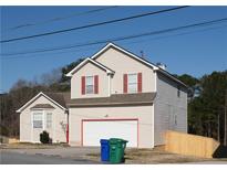 Charming two-story home features a large garage, neutral siding, red window trim, and a well-maintained yard at 5546 Wellborn Creek Dr, Lithonia, GA 30058