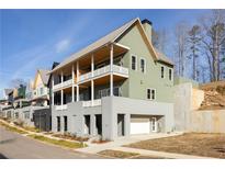 Modern exterior elevation view featuring multiple balconies and a two-car garage in a green and gray color scheme at 1235 Lupo Loop, Palmetto, GA 30268