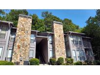 Charming condo exterior featuring stone accents, gray siding, and well-maintained landscaping at 4077 Woodridge Way, Tucker, GA 30084