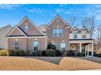 Stunning brick two-story home featuring mature landscaping and a covered front porch at 138 Lakestone Pkwy, Woodstock, GA 30188