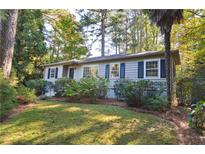 Charming one-story home with blue shutters, manicured landscaping, and mature trees providing shade at 1031 Lindridge Ne Dr, Atlanta, GA 30324