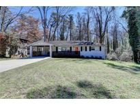 Charming one-story home with a manicured lawn, red front door, and attached carport at 2945 Monterey Dr, Decatur, GA 30032