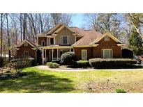 Charming two-story brick home with a well-manicured front yard, a covered porch, and mature trees at 1811 Mcconnell Rd, Grayson, GA 30017