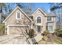Charming home featuring a two-car garage, manicured lawn, and a welcoming front entrance and beige stucco at 217 Colonial Dr, Woodstock, GA 30189
