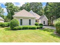 Charming home featuring a well-manicured lawn with lush greenery and a beige exterior at 370 Royal Birkdale Ct, Duluth, GA 30097