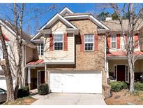 Charming townhome showcasing a brick facade, complemented by a one-car garage and well-maintained landscaping at 386 Creek Manor Way, Suwanee, GA 30024