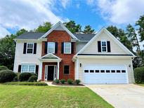 Charming two-story home featuring a well-manicured lawn, brick facade, and attached two-car garage at 1604 Hampton Hollow Trl, Lawrenceville, GA 30043