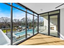 Bright living room featuring large windows, wood floors, and views of the pool and outdoor fireplace at 2520 Peachtree Nw Rd # 403, Atlanta, GA 30305