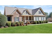 Charming home featuring stone accents, green siding, lush lawn, and well-maintained landscaping at 1656 Maes Overlook, Loganville, GA 30052