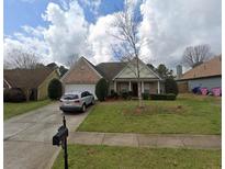 Traditional brick home featuring a well-manicured lawn, mature trees, and a two-car garage at 239 Gilliam Ct, Locust Grove, GA 30248