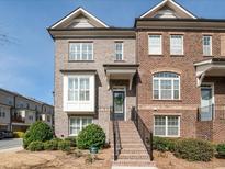 Charming brick townhome with well-manicured landscaping and inviting front entrance with steps at 1071 Township Sq, Alpharetta, GA 30022