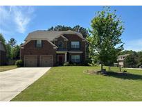 Charming two-story brick home with a well-maintained lawn, two-car garage, and inviting front entrance at 1211 Chapel Estates Way, Dacula, GA 30019