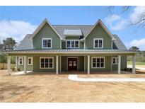 Charming two-story home with a covered porch, green siding, and a welcoming red front door at 529 Claude Scott Rd, Canton, GA 30115