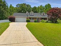 Charming one story home featuring a long driveway and an attached garage, with a well-manicured lawn at 12 Bonnie Glen Ln, Hampton, GA 30228