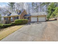 Brick home with a two-car garage and a long driveway surrounded by lush greenery and trees at 4149 Lynette Ne Ct, Kennesaw, GA 30144