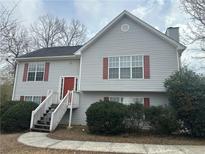 Charming two-story home features gray siding, red shutters and a welcoming front porch with wooden stairs at 1001 Fishback Way, Sugar Hill, GA 30518