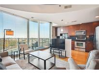 Modern living room featuring a large window with city views, sleek furniture, and an open-concept kitchen at 361 17Th Nw St # 2208, Atlanta, GA 30363