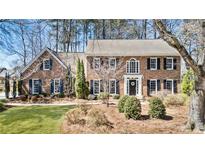 Beautiful two-story brick home with black shutters, manicured lawn, and mature trees at 741 Bentwood Trce, Alpharetta, GA 30005