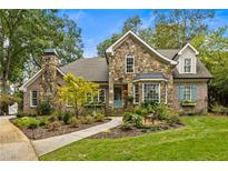 Charming stone home featuring a beautiful stone chimney, well-manicured landscaping, and a quaint front porch at 1993 Mount Vernon Pl, Dunwoody, GA 30338