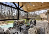 Inviting covered deck with a seating area, stylish furniture, ceiling fan, and views of the lush backyard and sparkling pool at 330 Chaffin Ridge Ct, Roswell, GA 30075