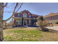 Inviting two-story brick home featuring a manicured front yard and covered front porch at 4065 Balsam Bark Dr, Cumming, GA 30028