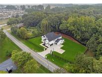 Stunning aerial view of a modern farmhouse with lush green lawn and surrounding trees at 3165 Hall Rd, Dacula, GA 30019
