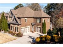 Beautiful brick home with a two-car garage and well-manicured landscaping and driveway at 5230 Harris Springs Dr, Cumming, GA 30040