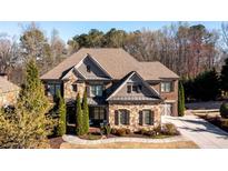 Charming two-story home with a stone facade, well-manicured landscaping, and a neatly paved driveway at 5230 Harris Springs Dr, Cumming, GA 30040